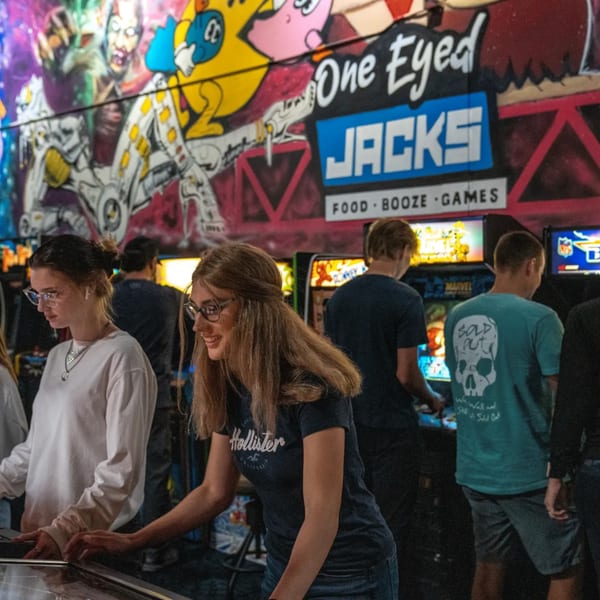 People playing pinball and arcade games at One Eyed Jacks bar-and-grill.
