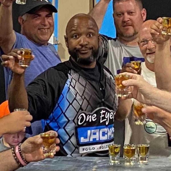 A group of men at One Eyed Jacks bar-&-grill raising shot glasses for a toast.