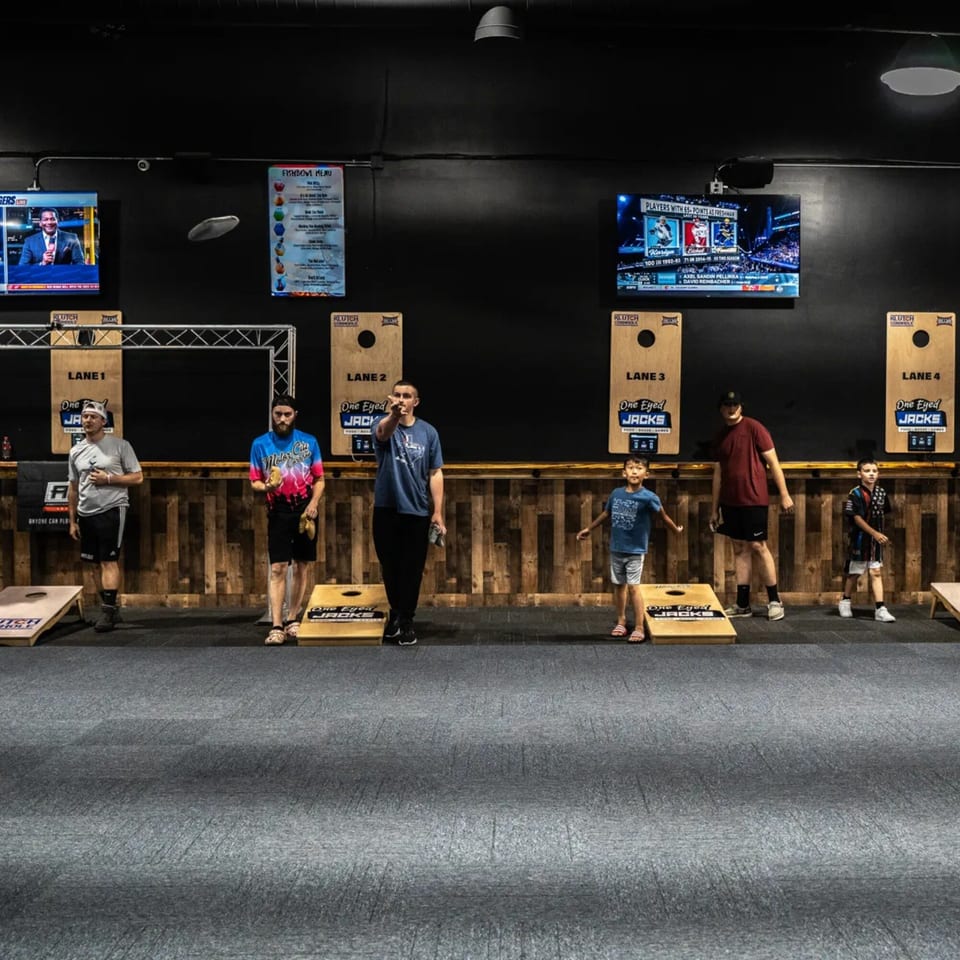 People of all ages playing cornhole at One Eyed Jacks, a bar-and-grill.
