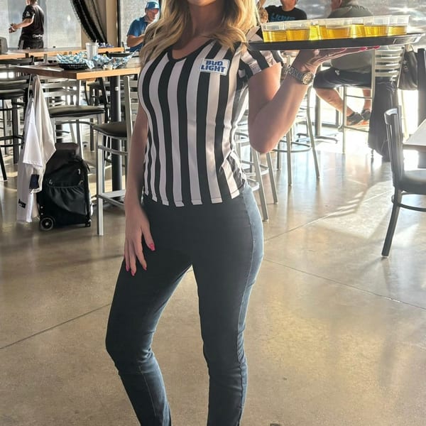 A server in a striped shirt with a "Bud Light" patch carries a tray of beer shots at One Eyed Jacks.