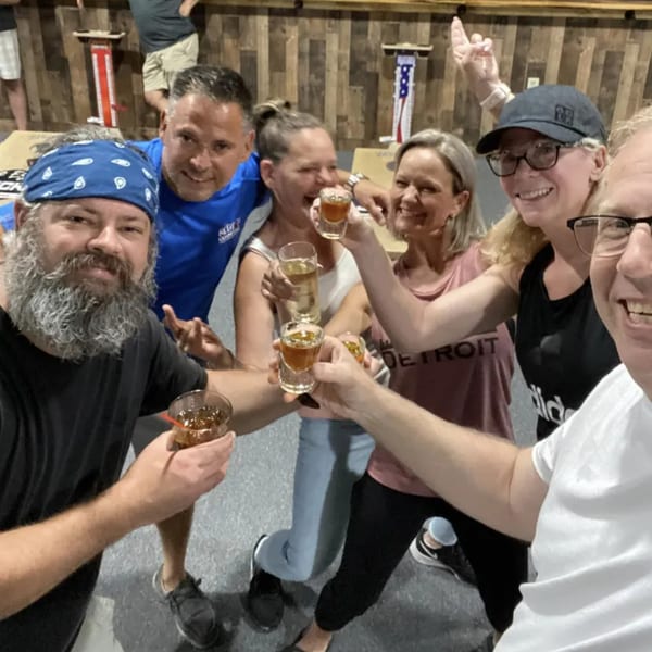 Six happy people toasting with drinks at One Eyed Jacks bar-&-grill.
