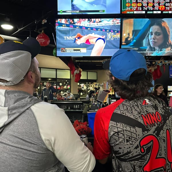 Two patrons at One Eyed Jacks bar watch sports and TV shows on multiple screens.