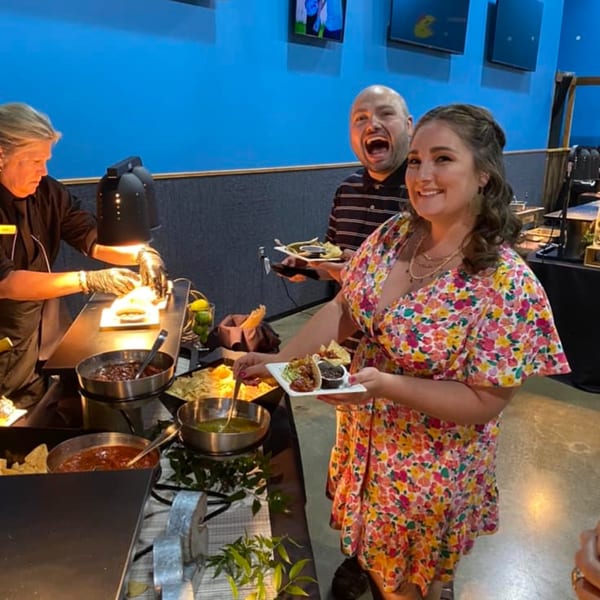 Guests at One Eyed Jacks enjoying a taco bar with a server preparing food.