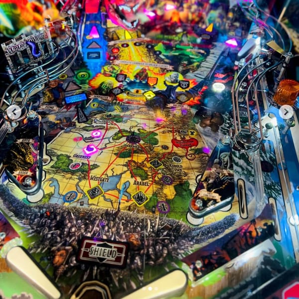 A vibrant, colorful pinball machine with a fantasy map and characters from One Eyed Jacks.