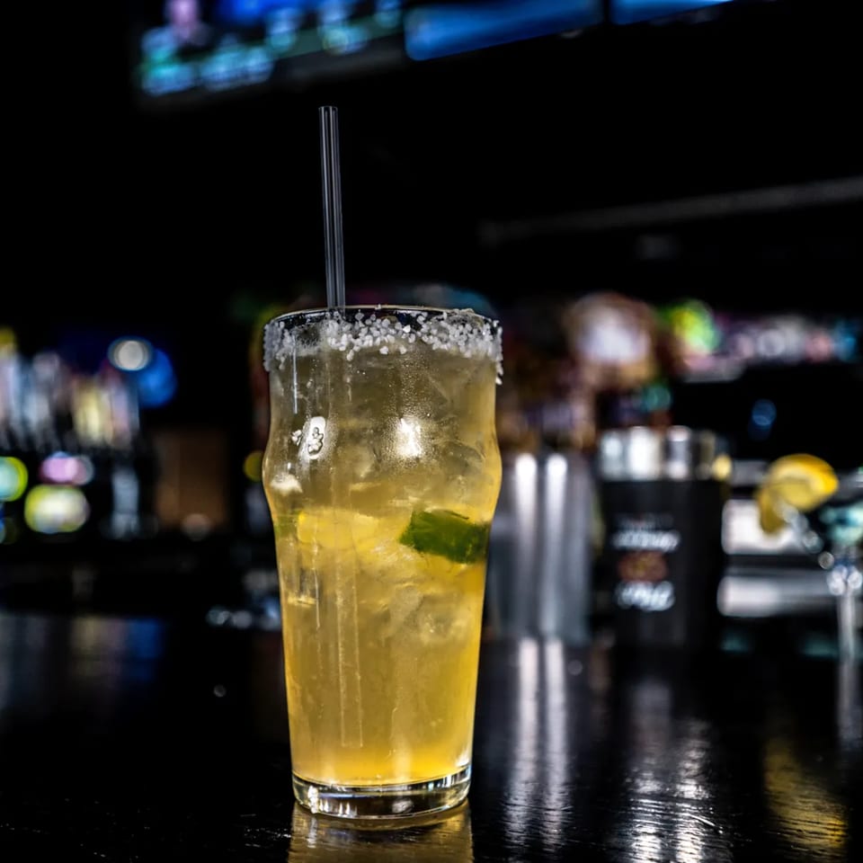 Salt-rimmed margarita with lime and ice on a dark bar at One Eyed Jacks.