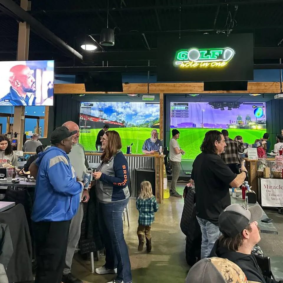 Patrons socialize and play golf simulators at One Eyed Jacks bar-and-grill.