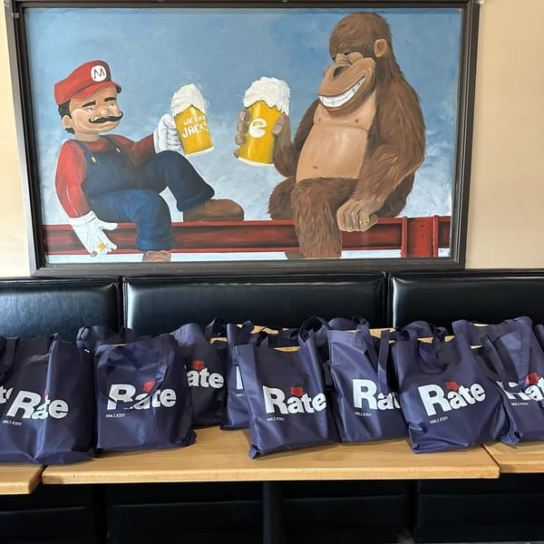 One Eyed Jacks mural of Mario and Donkey Kong holding beer mugs, above branded tote bags.
