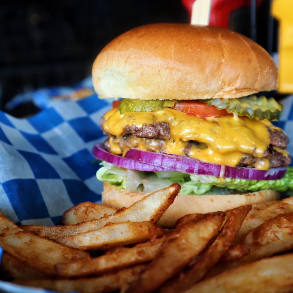 A double cheeseburger with lettuce, red onion, tomato, and pickles, served with steak fries.