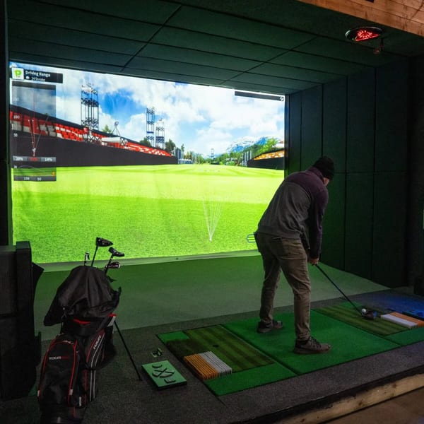A person playing golf on a large indoor simulator screen at One Eyed Jacks.