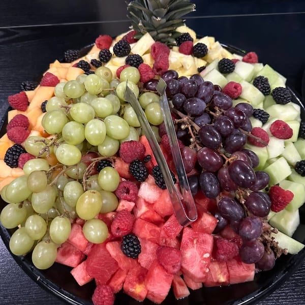 A large platter of fresh fruit, including grapes, watermelon, cantaloupe, honeydew, raspberries, and blackberries.