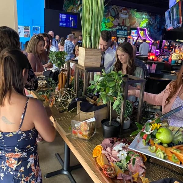 Guests gather around a buffet table with charcuterie and fruit at One Eyed Jacks bar-&-grill.