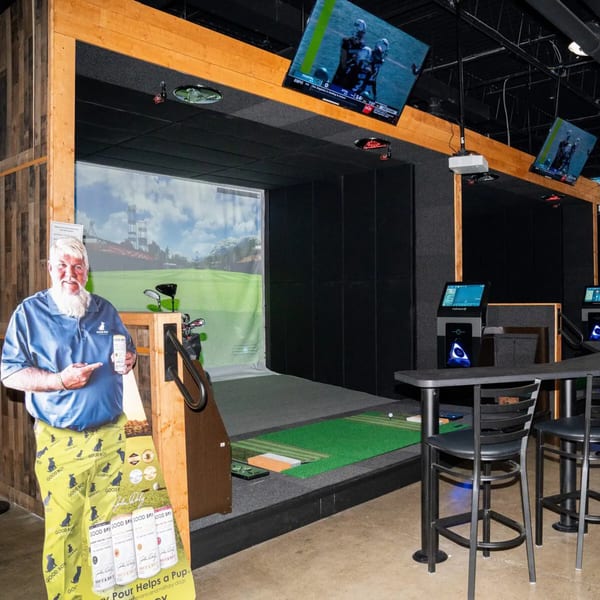 A golf simulator bay at One Eyed Jacks, with a cutout of a man holding a drink.