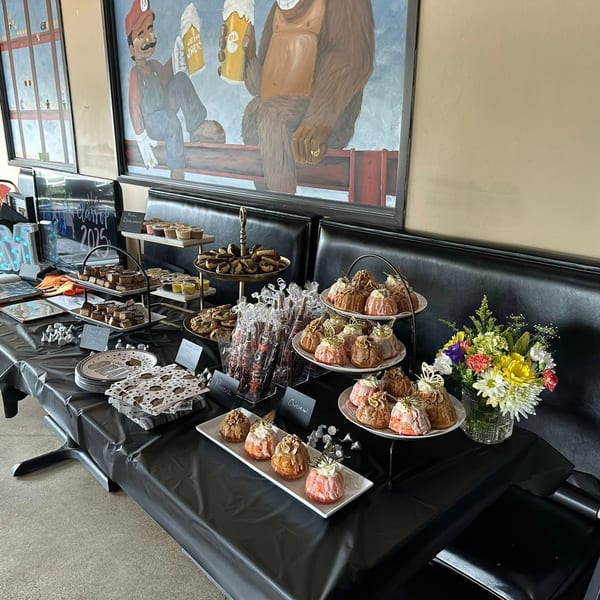 A dessert buffet with various pastries, cookies, and brownies, set against a mural at One Eyed Jacks.